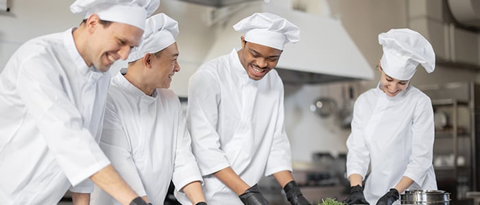 a group of cheerful chefs working collaboratively, focused on food preparation