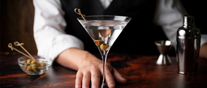 a bartender displays a martini glass with olives