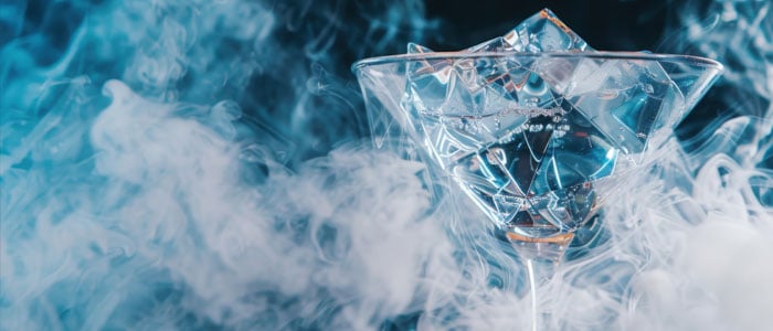 a cocktail glass with vibrant liquid and wisps of smoke rising