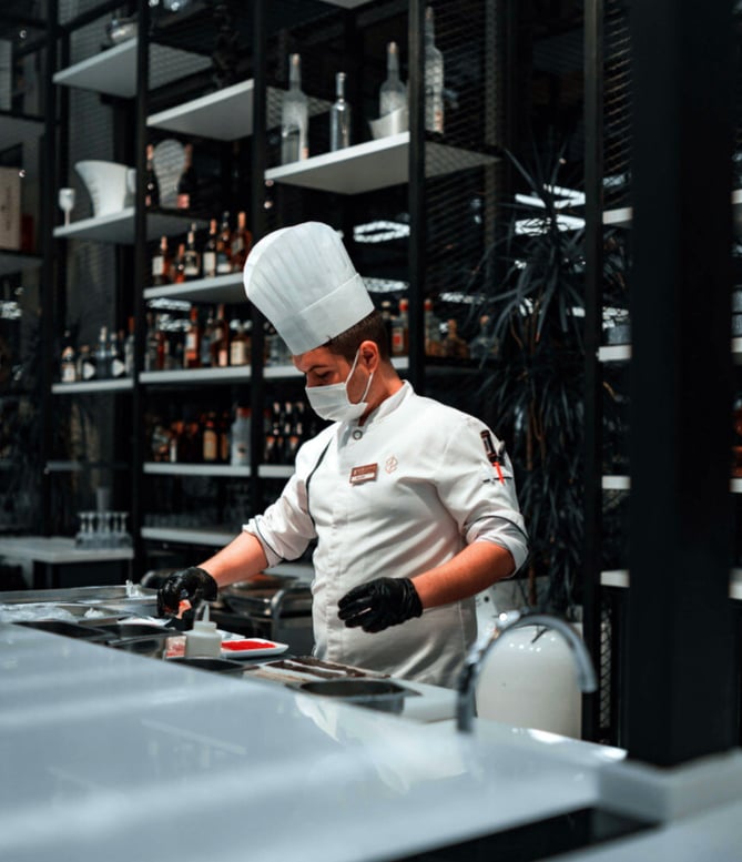 Chef wearing a toque, jacket, jacket, and gloves