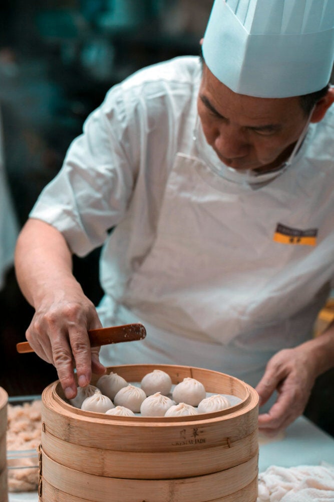 Head chef placing dumplings in a steamer
