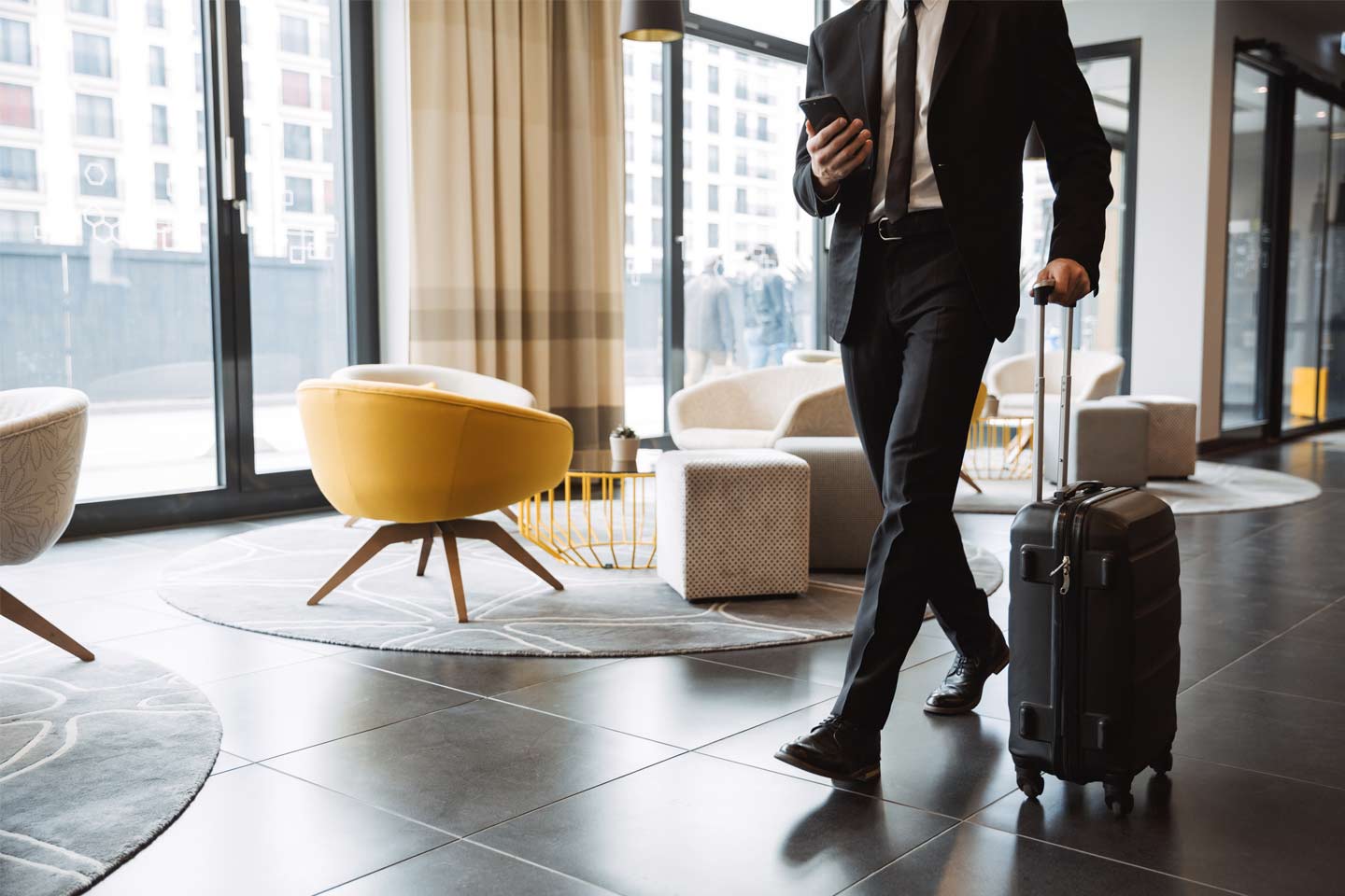 A professional man walking through the lobby with his handluggage case