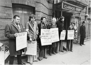 a group of people holding signs in front of a building